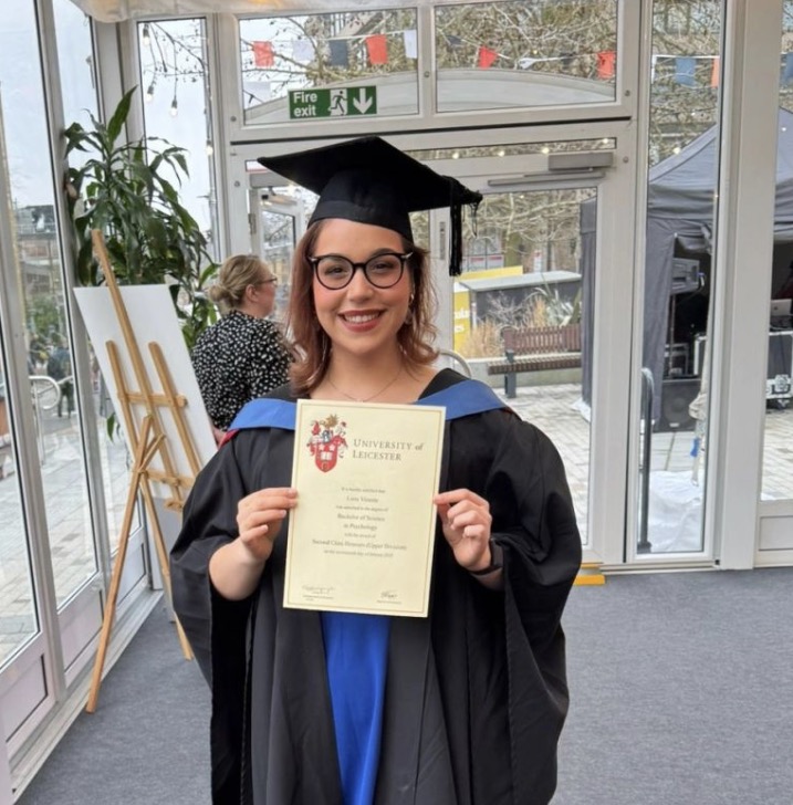 Luna celebrating her Psychology degree graduation, wearing her cap and gown